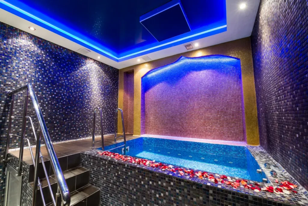 Steam room with blue lighting, mosaic walls, and a small pool