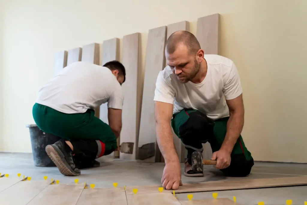 Two installers working on LVT floor tiles with spacers.