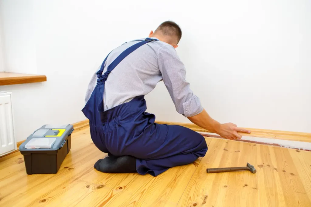Installer measuring wooden floor planks for precise fit.