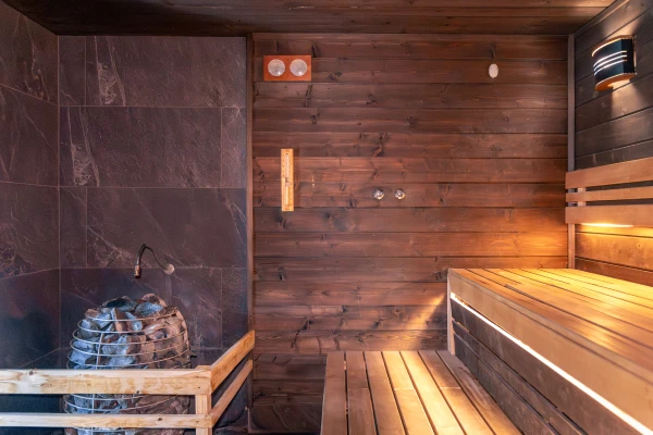 Interior of a sauna with wooden walls, benches, and a stone heater.