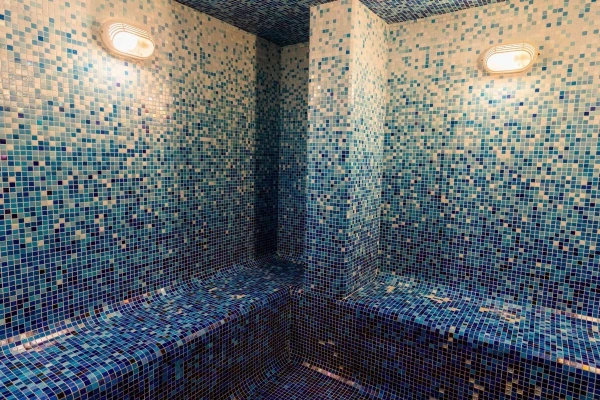 Steam room with blue mosaic tiles and soft ambient lighting