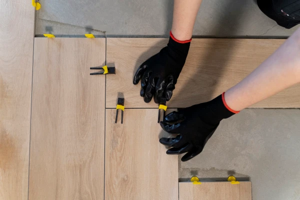 Person laying LVT tiles with spacers and gloves