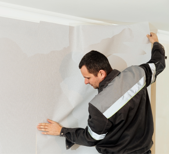 Professional installing wallpaper on white wall