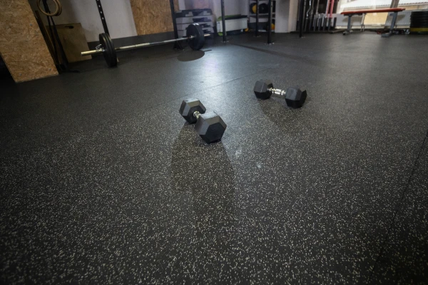 Gym floor with rubberized tiles and dumbbells placed on it.