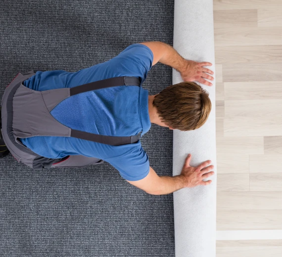 Person unrolling carpet onto the floor for installation