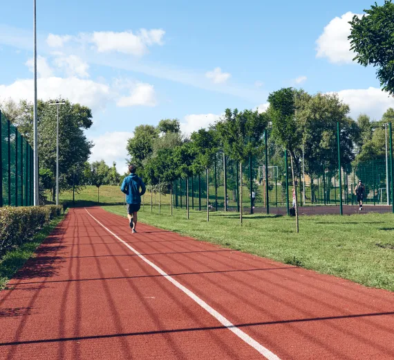 Runner jogging on a red outdoor running track.