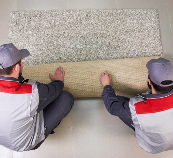 Carpet tile installation with workers laying down tiles.