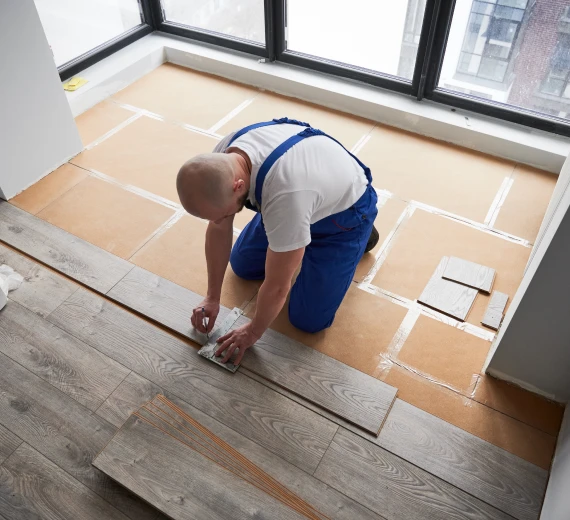 Person installing gym flooring tiles in a room.
