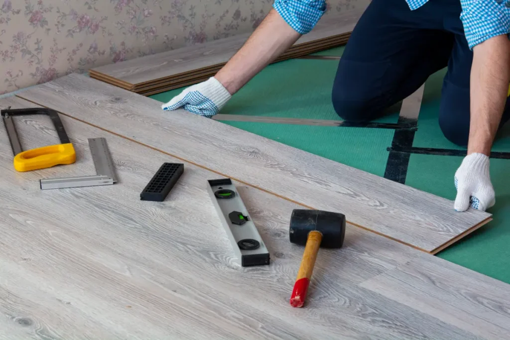 SPC flooring installation with tools like a mallet, square, and level.