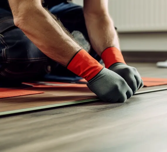 Two installers laying LVT flooring with trowels and spacers.