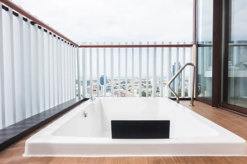 Outdoor Jacuzzi on a terrace with glass railing and urban background