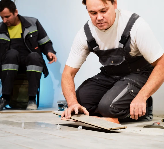 Workers installing wooden floor planks in a room